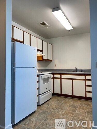 A kitchen with a white refrigerator and brown cabinets.