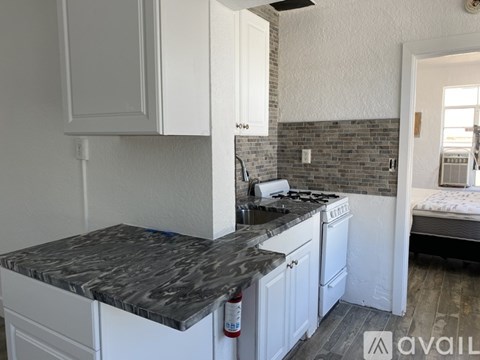 A kitchen with white cabinets and a marble countertop.