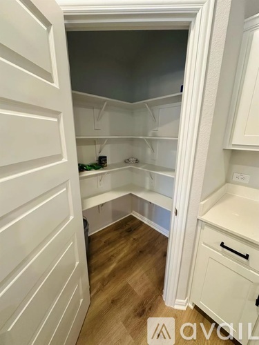 A white kitchen with a refrigerator and wooden floors.