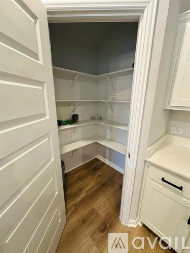 A white kitchen with a refrigerator and wooden floors.