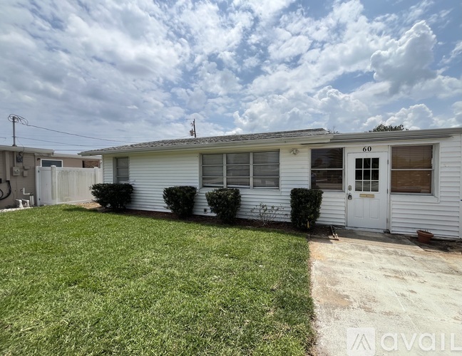 A house numbered 60 with a white exterior and a green lawn.