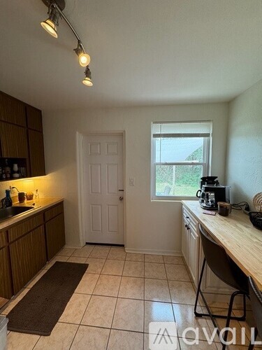 A kitchen with a sink, a window, and a brown rug on the floor.