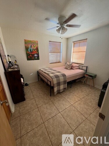A bedroom with a bed, a dresser, and a ceiling fan.