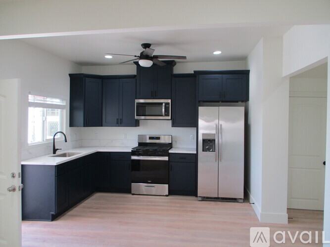 A kitchen with black cabinets and stainless steel appliances.