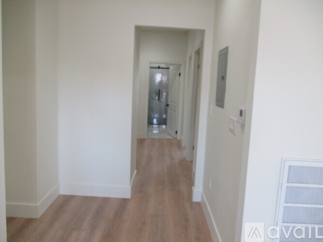 A hallway with wood flooring and white walls.