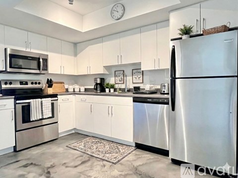 A kitchen with white cabinets and a black fridge.