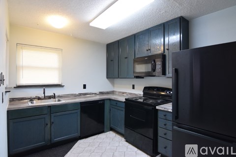 A kitchen with dark blue cabinets and a black refrigerator.