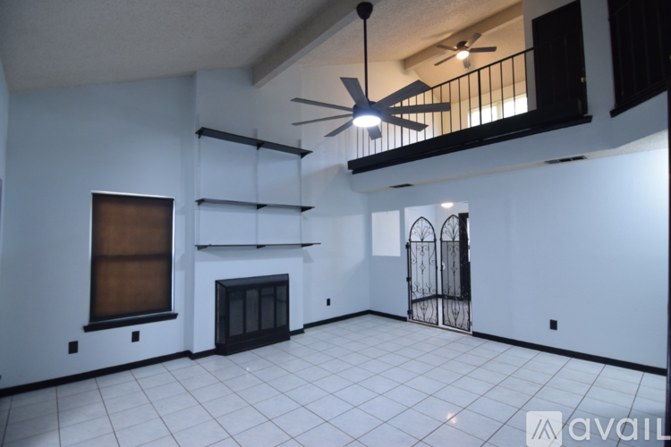 A spacious room with a fireplace and a ceiling fan.