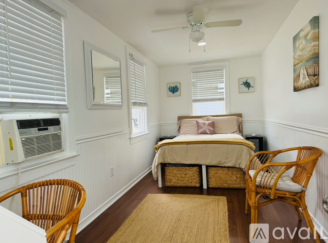A bedroom with a bed, chair, and window with blinds.