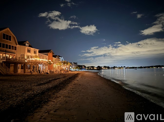 A beach scene at night with a row of lit buildings on the sand.