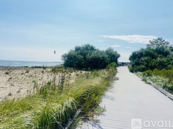 A wooden boardwalk leads through a grassy area to a beach.