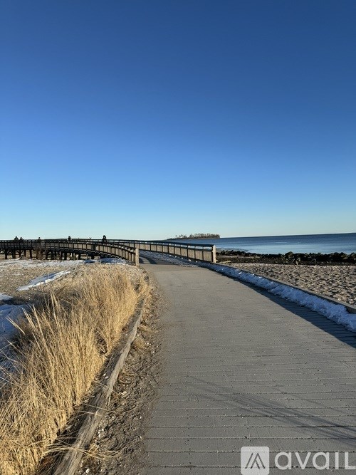 A pathway with a railing on one side and dry grass on the other.