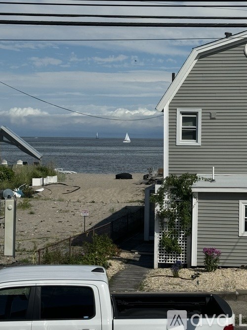A white van is parked in front of a house with a beach view.