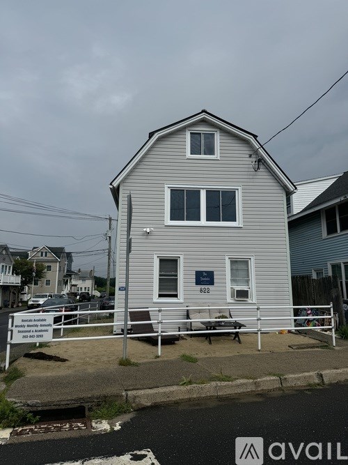 A two-story house with a grey facade and a white fence in front.