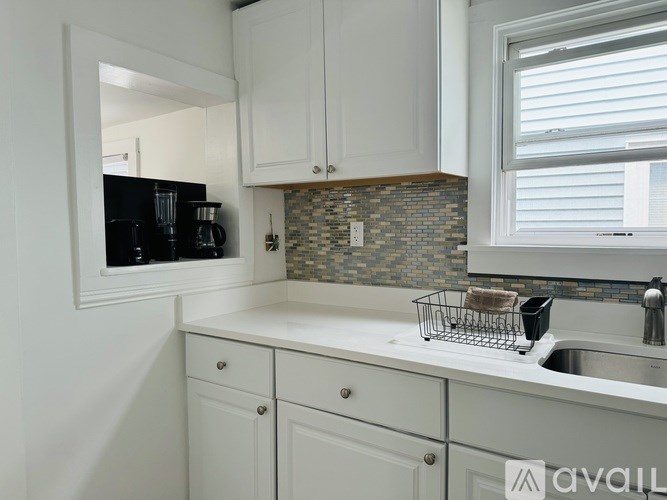 A kitchen with white cabinets and a black microwave.