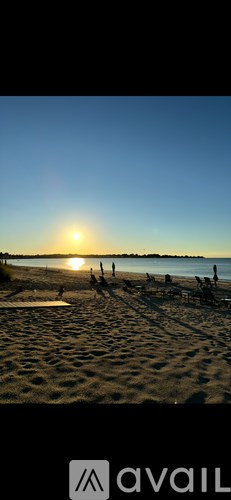 A beach scene with people and a sunset.
