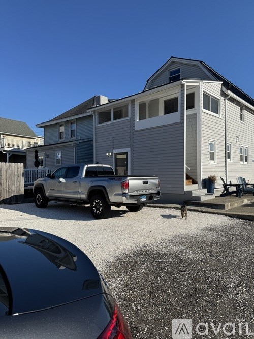 A silver truck is parked in front of a two-story house.