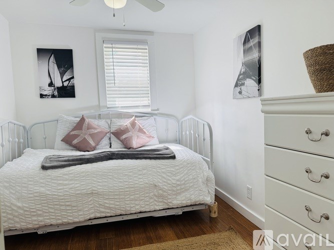 A white bed with a white headboard and a white dresser with three drawers.
