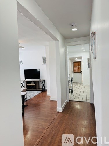 A hallway with wood floors and a television on a stand.