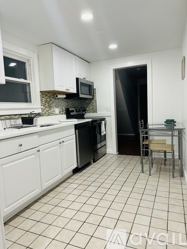 A kitchen with white cabinets and black appliances.