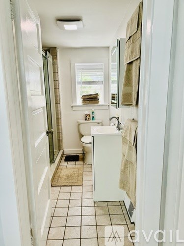 A bathroom with a toilet, sink, and a window.