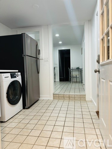 A kitchen with a black fridge and a washing machine.