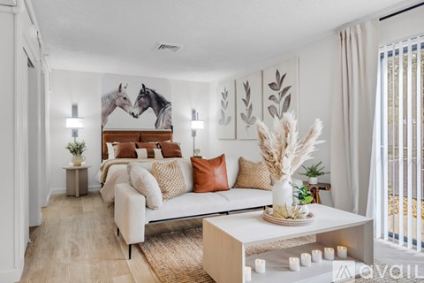 A living room with a white couch, a coffee table, and a painting of two horses on the wall.