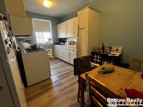 A kitchen with wooden floors and a table with a green cloth on it.