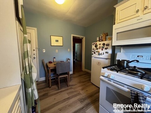 A kitchen with a stove, oven, and a dining table with chairs.