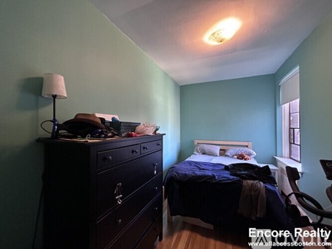 A bedroom with a bed, nightstand, and a dresser with a lamp on it.
