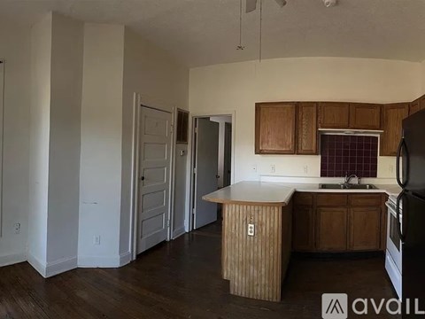 A kitchen with wooden cabinets and a black refrigerator.