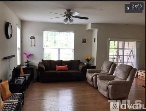A living room with a brown couch and a ceiling fan.