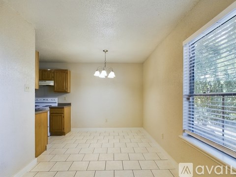 A spacious living room with tiled flooring and a window with blinds.