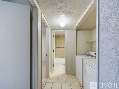 A hallway with a white door on the left and a white cabinet on the right.