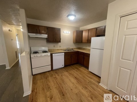 A kitchen with white appliances and wooden floors.