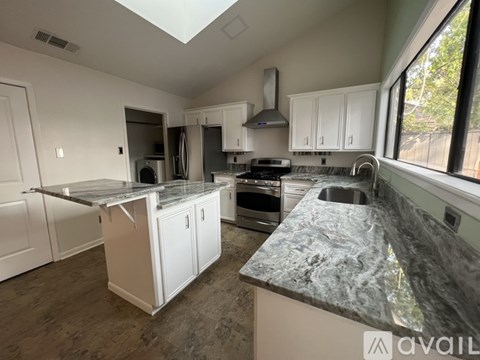 A kitchen with granite countertops and white cabinets is available for rent.