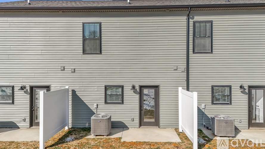 A grey house with a white fence and a small garden in front.