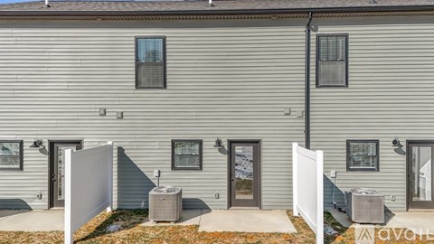 A grey house with a white fence and a small garden in front.