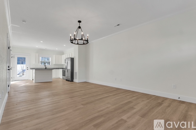 A large, empty room with wooden floors and a chandelier hanging from the ceiling.