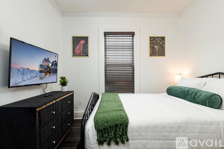 A bedroom with a bed, a dresser, and a television.