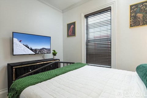 A bedroom with a bed, a television, and a painting on the wall.