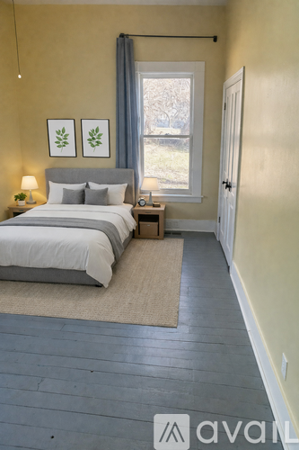 A room with wooden flooring and a window with a view of trees outside.