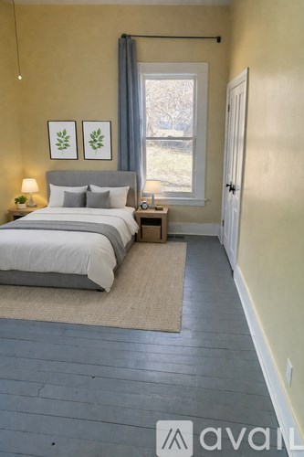 A room with wooden flooring and a window with a view of trees outside.