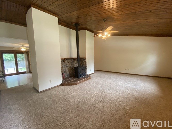 A spacious room with a fireplace and a ceiling fan.