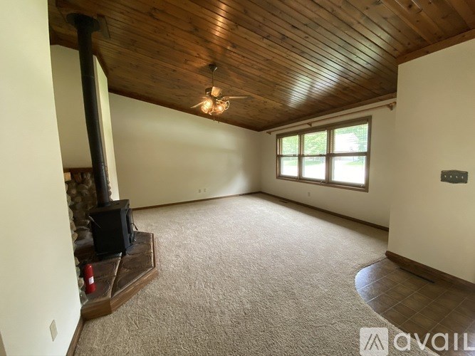 A room with a wood burning stove and a carpeted floor.