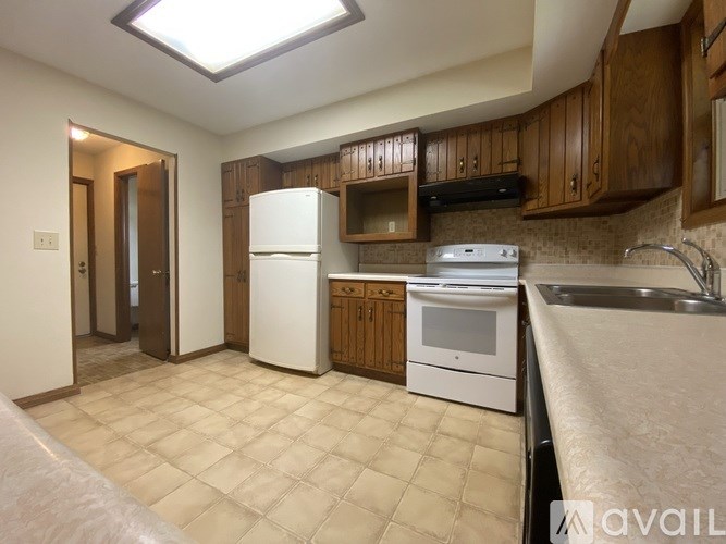 A kitchen with white appliances and brown cabinets.