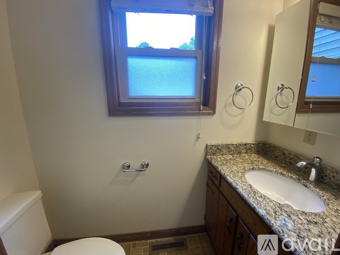 A bathroom with a toilet, sink, and mirror.