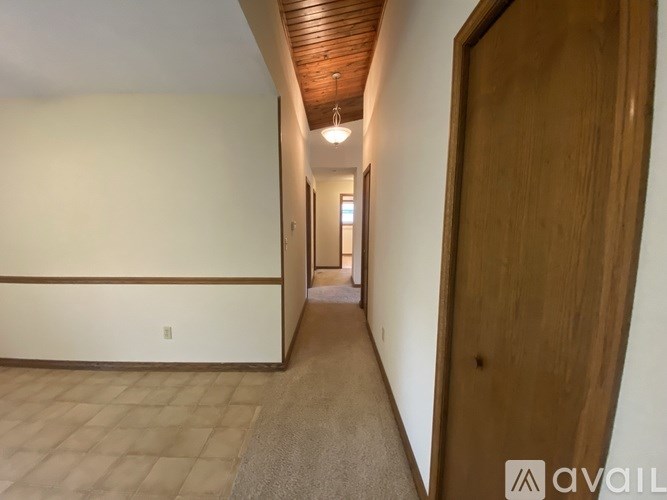 A long hallway with a wooden ceiling and a door on the right.