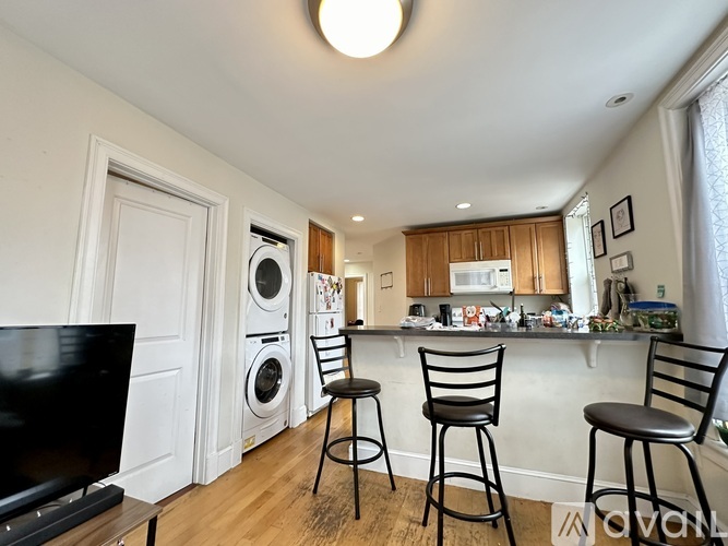 A kitchen with a bar stool and a television.