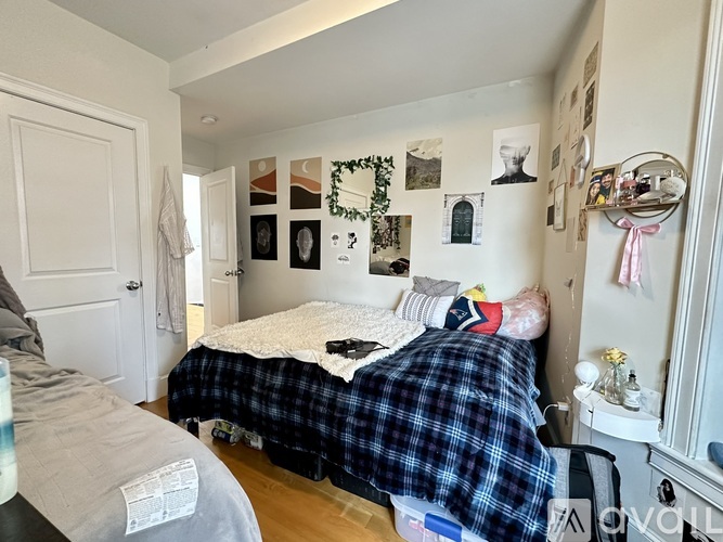 A bedroom with a bed covered in a plaid comforter and pictures on the wall.